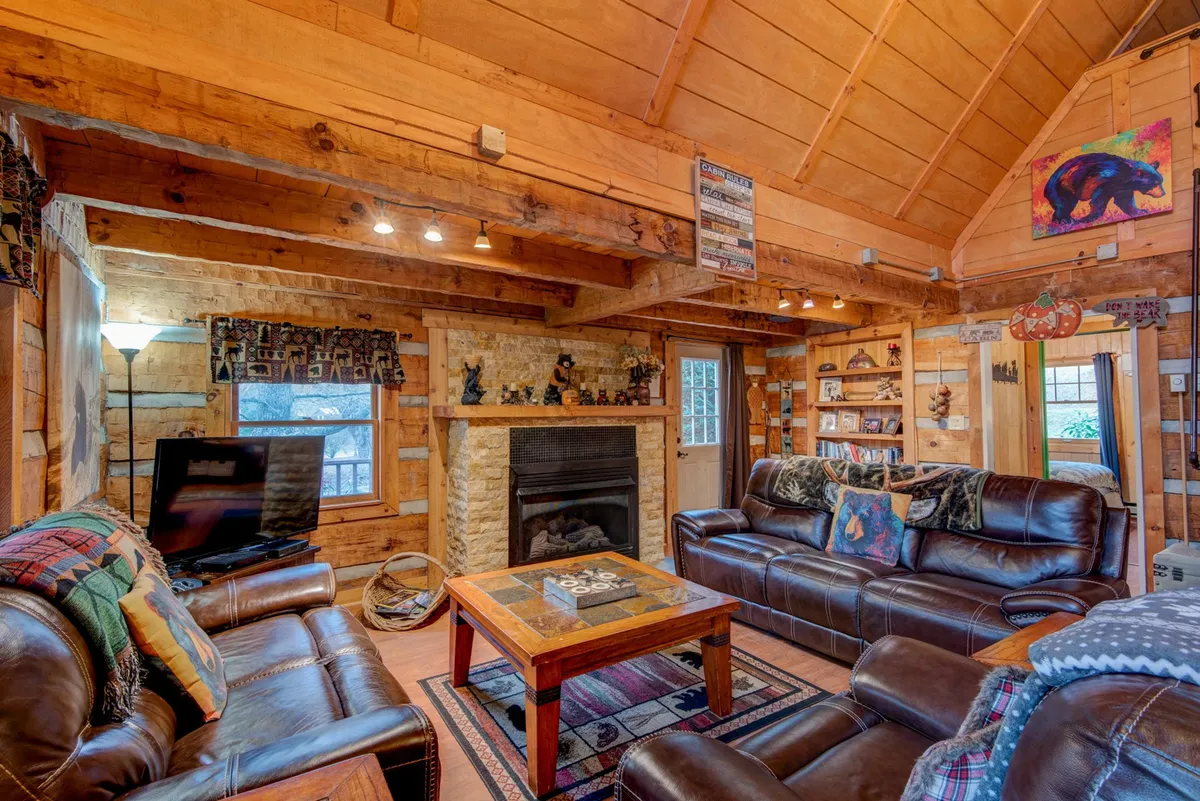 A cozy living area featuring a central fireplace, flanked by leather sofas and a coffee table, with decorative artwork providing a sense of place. The scene evokes warmth and togetherness, with soft lighting that hints at relaxation and socializing—perfect for unwinding after outdoor adventures.